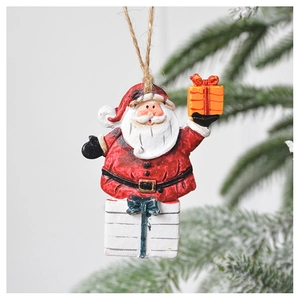Close-up of Santa Claus hanging ornament with gift boxes on a snowy Christmas tree branch