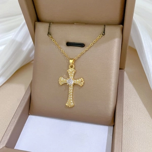 Detailed close-up of a gold baroque cross necklace with white zircon on satin