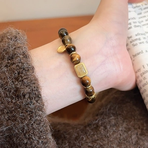 Detailed view of Tiger Eye beaded bracelet with hollow square pendant on a wrist