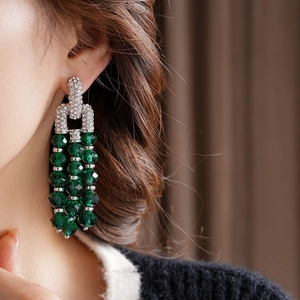 Detailansicht langer Vintage-Ohrringe mit grünen Kristallen und glitzernden Strasssteinen