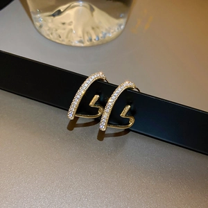 Macro shot of gold geometric hoop earrings featuring micro-set sparkling zircon stones