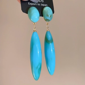 Detail view of teal teardrop earrings with gold metal rings and turquoise texture