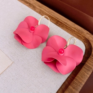 Detailed macro view of matte pink floral earrings with gold hooks on linen texture