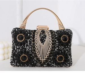 Close-up of black evening clutch with handcrafted crystal flowers and gold metal handle