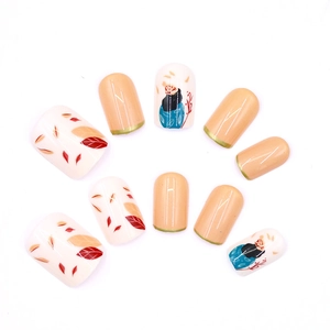 Short press-on nails featuring autumn leaf patterns and gold accents on a nude base