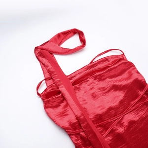 Detail of red satin slip dress neck showing silk texture and delicate straps