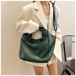 Detail of dark green textured leather hobo bag worn with a chic beige suit outfit
