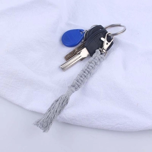 Detail of hand-woven grey cotton cord keychain with decorative fringe and metal clasp