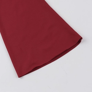 Détail des poignets évasés sur une robe en maille rouge foncé avec texture de tissu nette