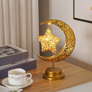 Détail de la lampe lune dorée avec étoile en rotin tressé et lumière LED chaude sur bois