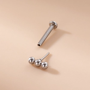 Minimalist 16G stainless steel labret stud featuring a three-bead top design on a plain background