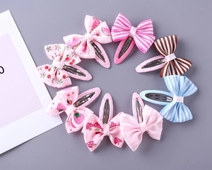 Detail view of eight assorted fabric bow hair clips with stripes and fruit patterns