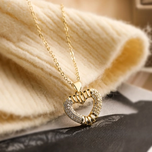Elegant gold plated heart pendant necklace with sparkling zircons on a knit texture