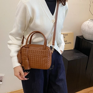 Brown hand-woven leather crossbody bag with tassel detail and adjustable shoulder strap