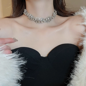 Close-up of a silver rhinestone choker necklace on a model wearing a white fur coat