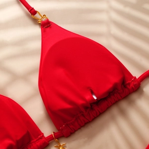 Detail of red bikini top with golden starfish charm and palm leaf shadow background