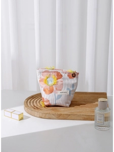 Floral embroidered canvas cosmetic bag with tassel and flower pendant on wooden stand