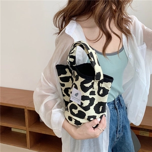 Detail of animal print tote bag featuring leopard patterns and a minimalist logo patch