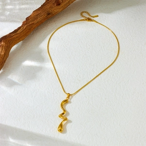Minimalist gold plated stainless steel necklace with abstract curved pendant on wood