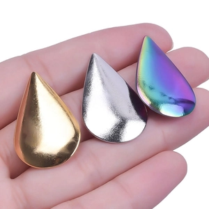 Three teardrop metal charms in gold silver and rainbow finish shown on palm