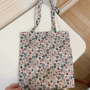 Detail view of floral canvas tote bag with dense pink and green flower patterns