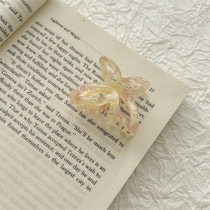 Detail view of a butterfly acetate hair claw clip with floral patterns on a vintage book