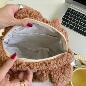 Detail view of the plush tote bag interior featuring cream lining and zipper pocket