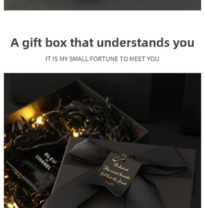 Detail of luxury black kraft gift box with silk ribbon bow and warm LED string lights inside