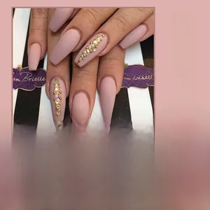 Detail of matte pink coffin press-on nails with rhinestone and gold bead accents