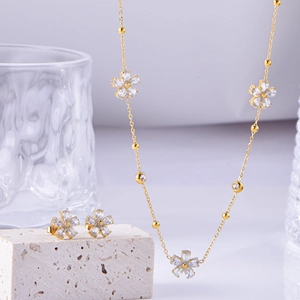 Gold flower jewelry set with white zircon necklace and earrings on stone display