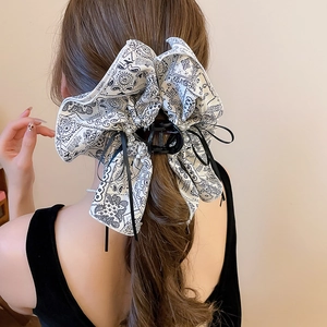 Detail of fabric bow hair claw with paisley print and faux pearls on model hairstyle
