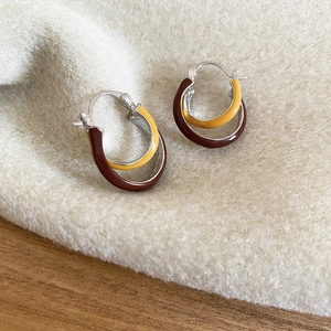 Detail of retro double-layer enamel hoop earrings in brown and yellow on soft plush fabric