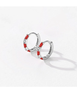 Détail de créoles en argent S925 avec motifs en émail rouge et pierres de zircon claires