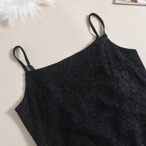 Détail d'un body en dentelle noire avec motifs floraux et fines bretelles