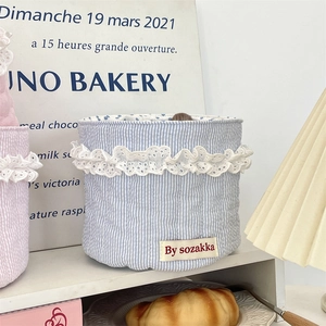 Close-up of light blue striped fabric storage basket with white lace and brand tag