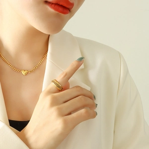 Golden heart pendant necklace and textured ring set on elegant model in white blazer