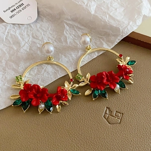 Detail of bohemian hoop earring with red flower, green leaves, and 925 silver pearl stud