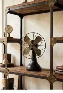 Detail of vintage industrial metal desk fan on a rustic bookshelf with retro props
