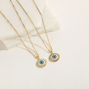 Golden titanium evil eye necklace with colorful zircon stones on marble background