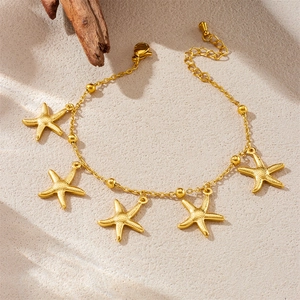 Bohemian gold stainless steel starfish charm bracelet on beach sand background