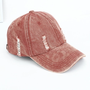 Detail showing distressed denim baseball cap with frayed holes and vintage brick red finish