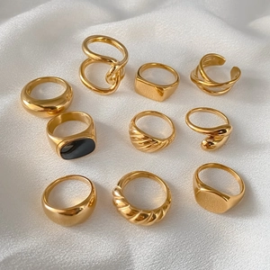 Macro-opname van diverse minimalistische vergulde ringen op een witte getextureerde stof.