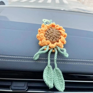 Handmade crochet sunflower car hanging ornament on a black leather car dashboard