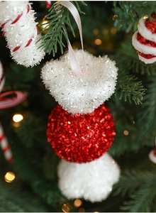 Sparkling red and white sequined ball ornament hanging on a Christmas tree branch