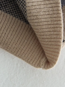 Macro shot of beige diamond jacquard knit vest with ribbed hem and thick wool texture