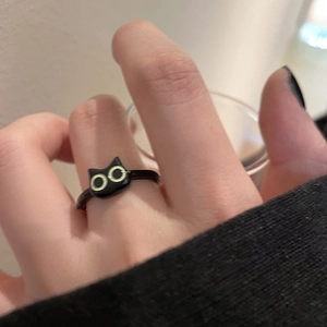 Detailed view of a cute black cat ring with yellow eyes worn on a finger