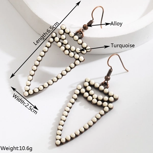 Détail de boucles d'oreilles flèches en bronze bohème avec incrustations de turquoise