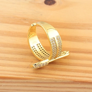 Detail of gold nail wrap ring featuring micro-pave cubic zirconia on wood background