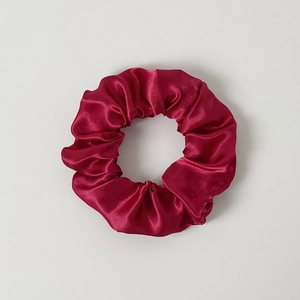 Close-up of a red LED glowing scrunchie with a glossy satin finish on a white background
