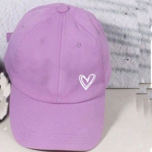 Close-up of heart embroidery on purple baseball cap with adjustable strap detail